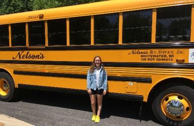 Kim poseert bij een gele Amerikaanse schoolbus