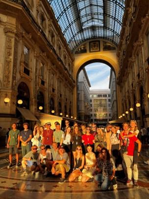 Een groep van ongeveer 25 jongeren poserend voor de foto in de avondzon in een historische galerij in Milaan